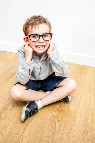 Niño feliz con gafas nerd cubriendo las orejas para la autoestima — Foto de Stock