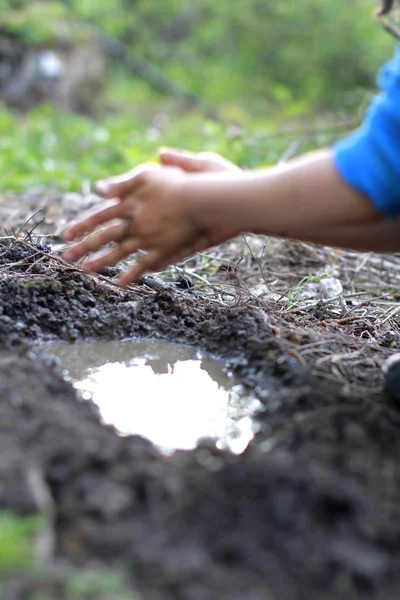 Stock image child playing with mud - blur hands for focus on pond