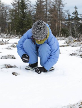Genç kış çocuğu test ediyor, dokunuyor, ağaçların üzerinde karla oynuyor.