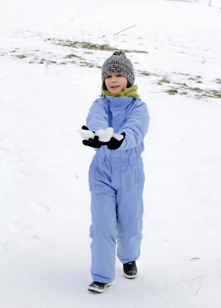 Улыбающийся зимний ребенок в лыжном снаряжении, гуляющий по снегу — стоковое фото