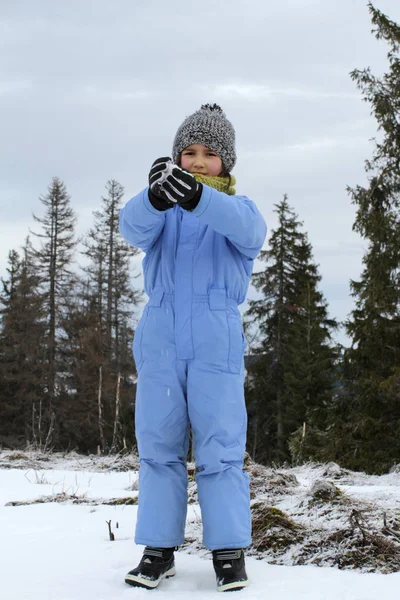 Smiling winter child with ski outfit playing with cold snow — 스톡 사진