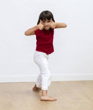 motivasyon, enerji ve canlılığı beyaz arkaplan üzerinde ifade etmek için yüzün yanında çift baş parmak gösteren motive çocuk