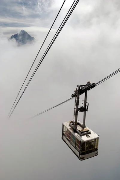 Cabine à câbles sortant des nuages — Photo