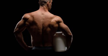 Siyah arka planda protein kavanozu olan kaslı vücut geliştirici. Spor beslenmesi. Vücut geliştirme besin desteği, egzersiz, sağlıklı yaşam tarzı konsepti..