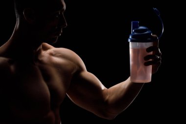 Siyah arka planda protein kavanozu olan kaslı vücut geliştirici. Spor beslenmesi. Vücut geliştirme besin desteği, egzersiz, sağlıklı yaşam tarzı konsepti..