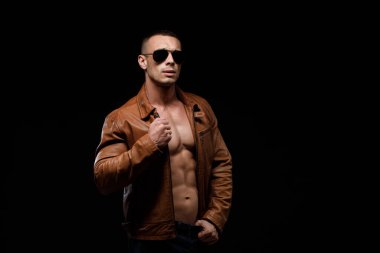 Siyah arka planda basın mensuplarını gösteren kot pantolonlu kaslı spor mankeni. Sportif, sağlıklı, güçlü kaslı adamın moda portresi. Seksi gövde..