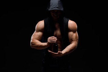 Siyah arka planda protein kavanozu olan kaslı vücut geliştirici. Spor beslenmesi. Vücut geliştirme destek malzemeleri, spor, egzersiz, sağlıklı yaşam tarzı konsepti.