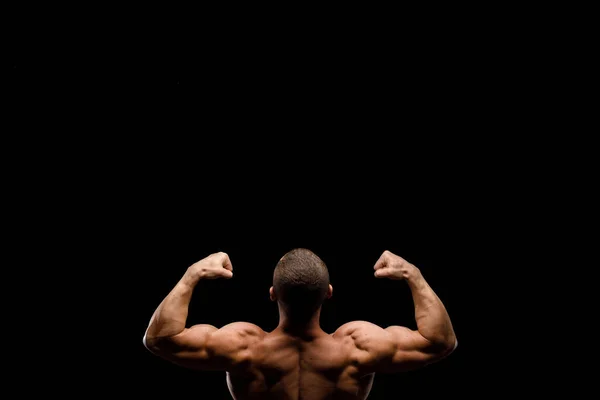 Muscular bodybuilder on a black background. Sports nutrition. Bodybuilding nutrition supplements, workout, healthy lifestyle concept.