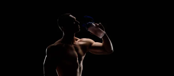 Siyah arka planda protein kavanozu olan kaslı vücut geliştirici. Spor beslenmesi. Vücut geliştirme besin desteği, egzersiz, sağlıklı yaşam tarzı konsepti..