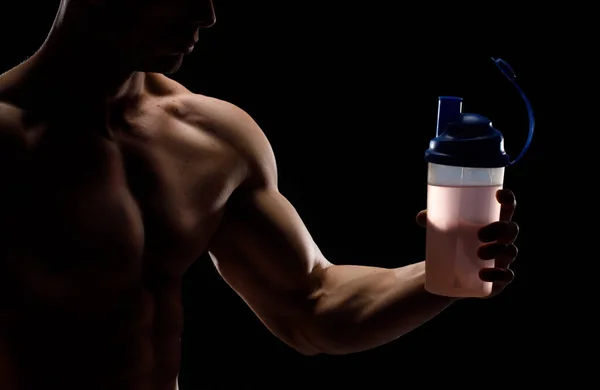 Muscular bodybuilder with jar of protein on a black background. Sports nutrition. Bodybuilding nutrition supplements, workout, healthy lifestyle concept.