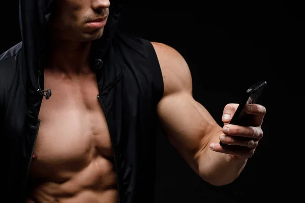 暗い背景に手を携帯電話で筋肉のボディビルダー スポーツ栄養 ボディビルディング栄養補助食品 スポーツ ワークアウト 健康的なライフスタイルのコンセプト — ストック写真