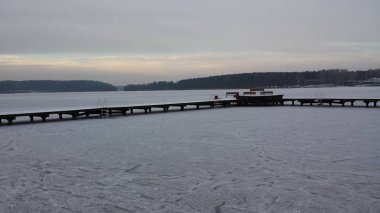 Donmuş göl ve bulutlu bir günde bir ahşap iskelesi