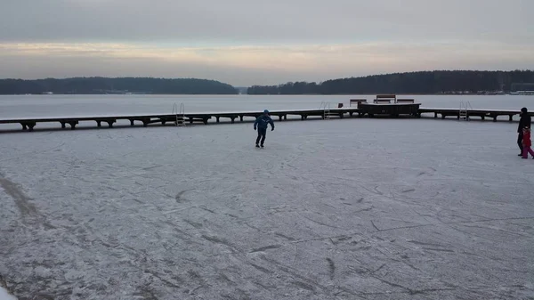 Skater jeździ na zamarzniętym jeziorze w pochmurny dzień — Zdjęcie stockowe