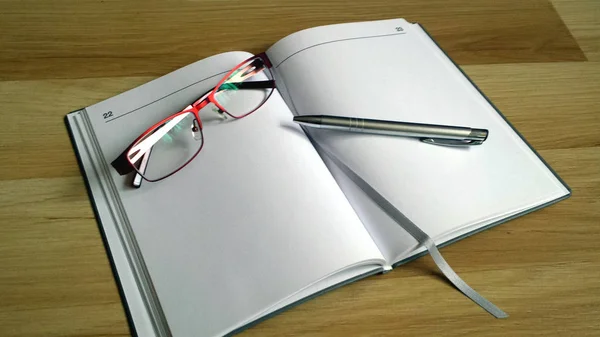 Büroarbeit Aufgeschlagenes Notizbuch Mit Weißen Seiten Brille Und Silbernem Stift — Stockfoto