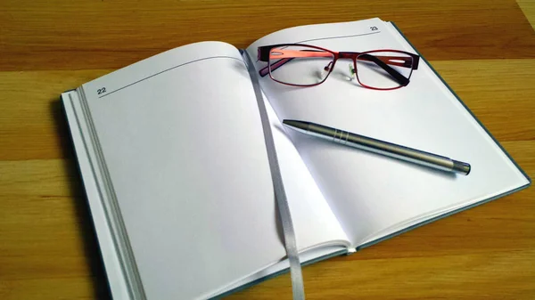 Büroarbeit Aufgeschlagenes Notizbuch Mit Weißen Seiten Brille Und Silbernem Stift — Stockfoto