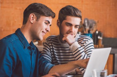 gay çift dizüstü bilgisayar kullanırken konuşuyor