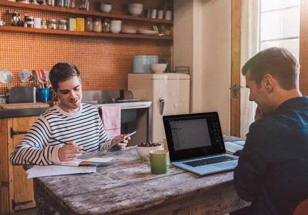 Vrienden zitten in de keuken werken samen — Stockfoto