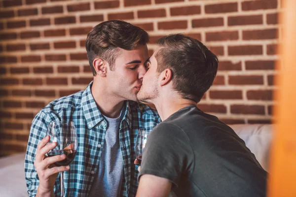 Gay couple drinking red wine and kissing — Stock Photo, Image