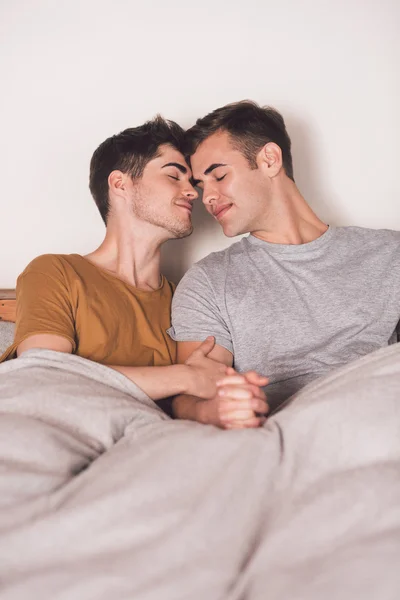손을 함께 침대에서 게이 커플 잡고 — 스톡 사진