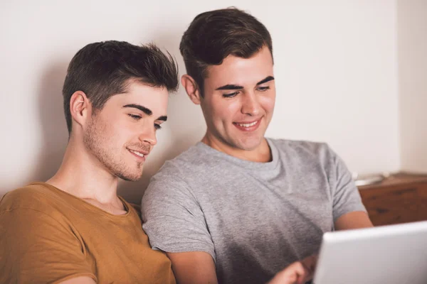 Gay couple using tablet while lying in bed — Stock Photo, Image