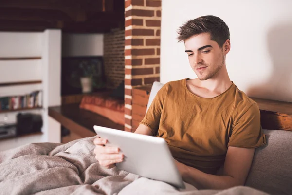 Man using tablet while sitting up in bed — Stock Photo, Image