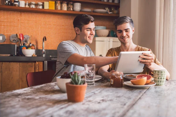 Gay par äter frukost och använda surfplatta — Stockfoto