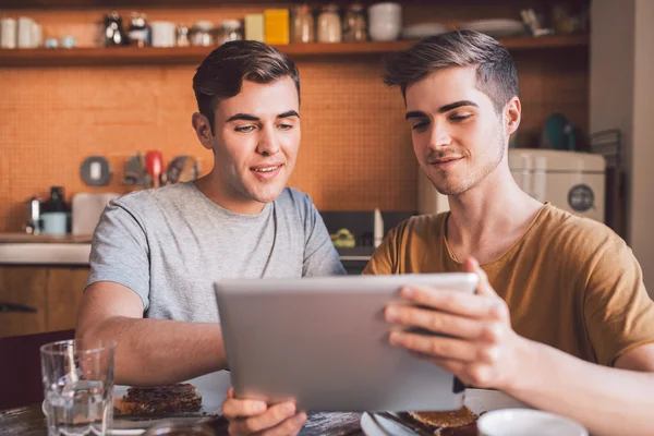 Gay couple eating breakfast and using tablet — Stock Photo, Image