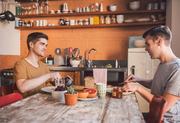 Gay couple talking and eating breakfast — Stock Photo, Image