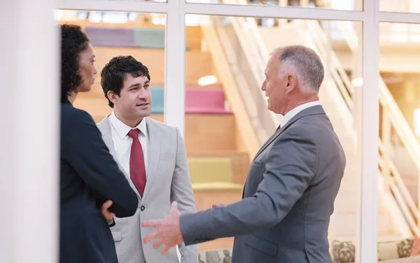 Pessoas de negócios conversando juntos enquanto de pé no lobby — Fotografia de Stock