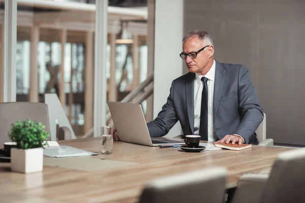 Zakenman in pak met laptop in bestuurskamer — Stockfoto