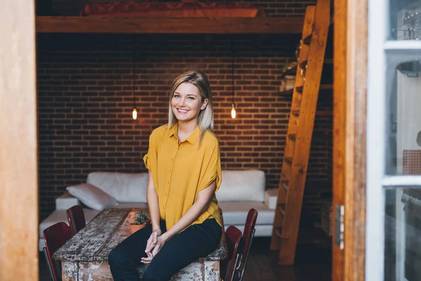 Woman sitting on table of modern apartment — Stock Photo, Image