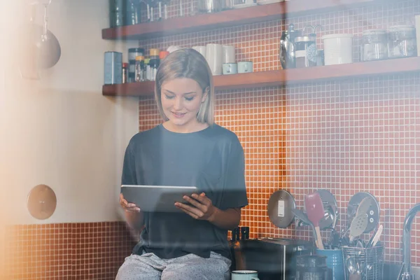 Vrouw met behulp van Tablet PC zittend op teller — Stockfoto