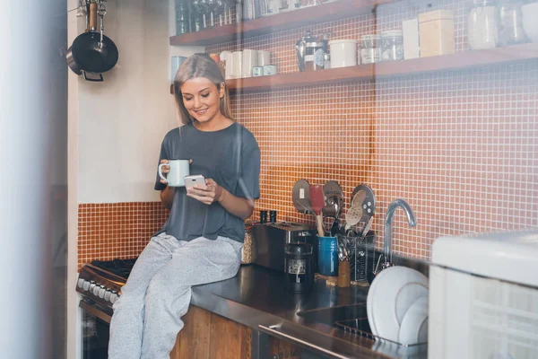 Kvinna dricker kaffe och med hjälp av mobiltelefon — Stockfoto