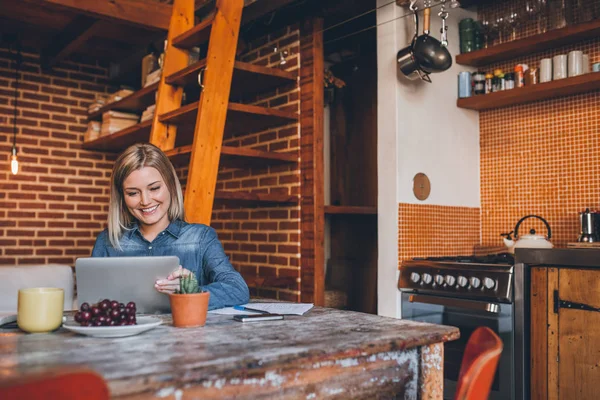 Woman sitting at table and using tablet — Stock Photo, Image