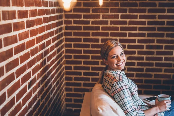 Mulher sentada no sofá e bebendo café — Fotografia de Stock