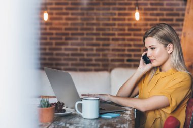 Kadın telefonda konuşurken ve dizüstü bilgisayar kullanarak