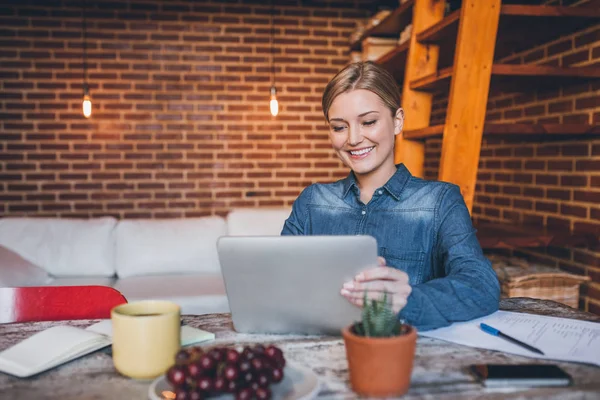 Žena sedí u stolu a používání tabletu — Stock fotografie