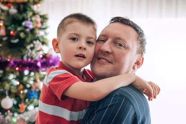 Father hugging son in front of Christmas tree — Stock Photo, Image