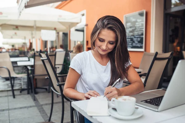 Lachende vrouw schrijven in een café — Stockfoto