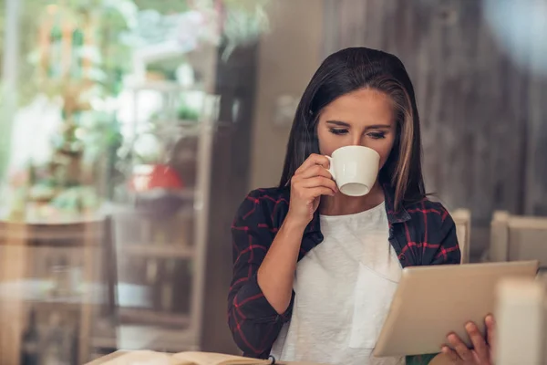 Jonge vrouw met behulp van een digitaal tablet op haar favoriete cafe — Stockfoto