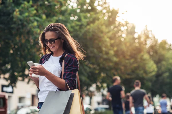 Ung kvinna texting medan du njuter av en dag med shopping — Stockfoto