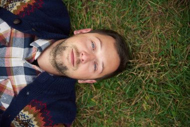 gülümseyen genç adam çim üzerinde yalan  
