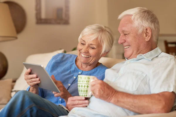 Старша пара використовує планшет на дивані — стокове фото