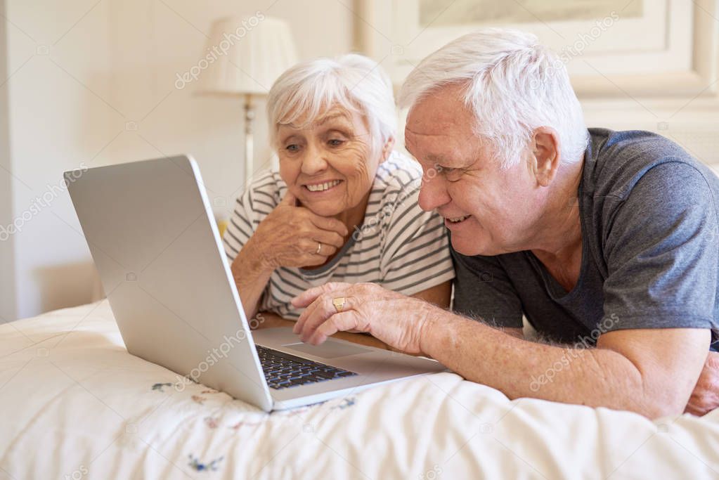 couple using laptop in bed