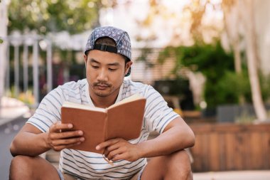 Okuma şapkalı Asyalı adam 