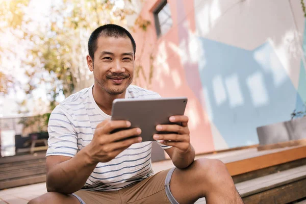 Homem sorrindo e usando tablet digital — Fotografia de Stock