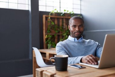 Bir ofiste bir dizüstü bilgisayar üzerinde çalışan genç Afrika işadamı