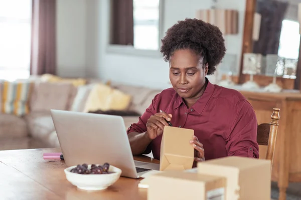 Woman writing addresses on package — Stock Photo, Image