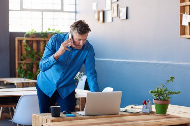 telefonda konuşmak ve dizüstü bilgisayar kullanarak iş adamı