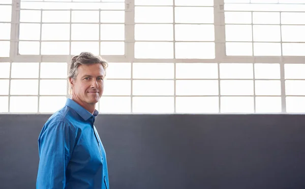 Mature businessman standing alone by windows — Stock Photo, Image